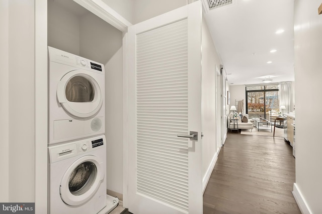 washroom with stacked washer and dryer and hardwood / wood-style flooring