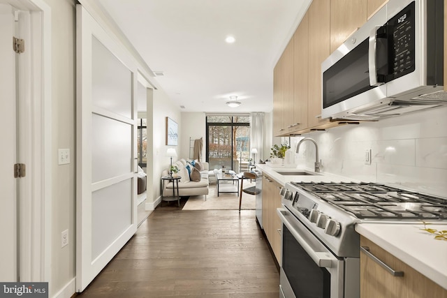 kitchen with sink, backsplash, stainless steel appliances, dark wood-type flooring, and light brown cabinets