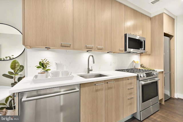 kitchen featuring sink, light brown cabinets, dark hardwood / wood-style flooring, stainless steel appliances, and decorative backsplash