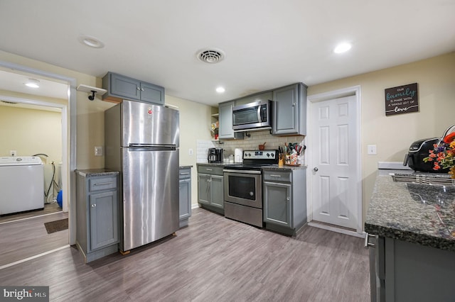 kitchen featuring washer / clothes dryer, appliances with stainless steel finishes, gray cabinets, and hardwood / wood-style floors