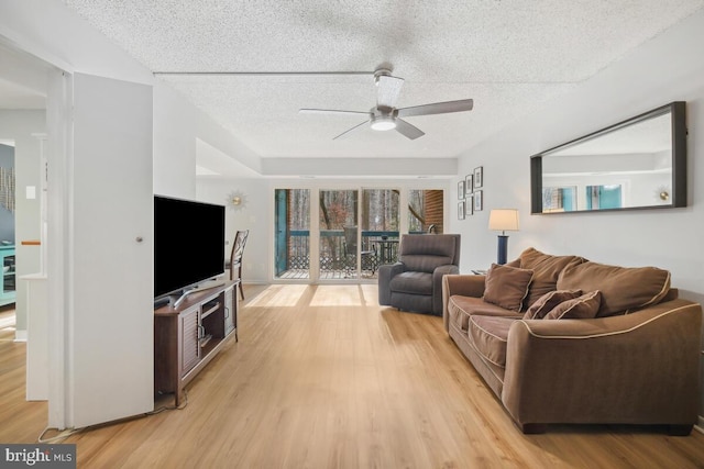 living room featuring ceiling fan, light hardwood / wood-style flooring, and a textured ceiling