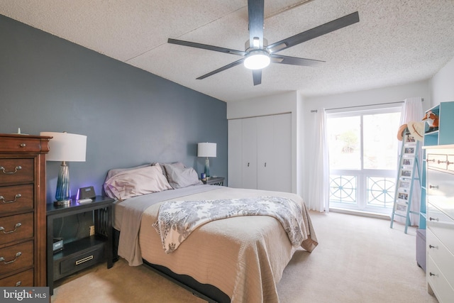 carpeted bedroom featuring ceiling fan, a closet, and a textured ceiling