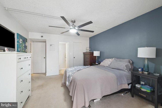 bedroom featuring ceiling fan, light colored carpet, and a textured ceiling