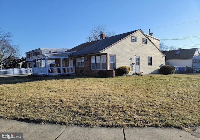 view of front of house featuring a sunroom and a front yard