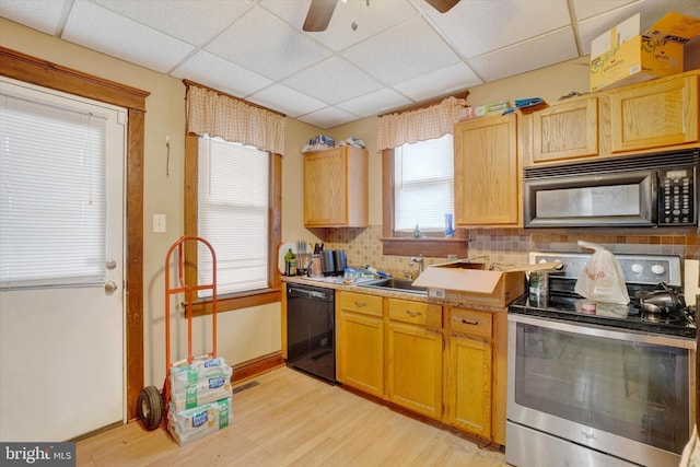 kitchen featuring light hardwood / wood-style floors, black appliances, decorative backsplash, sink, and a paneled ceiling