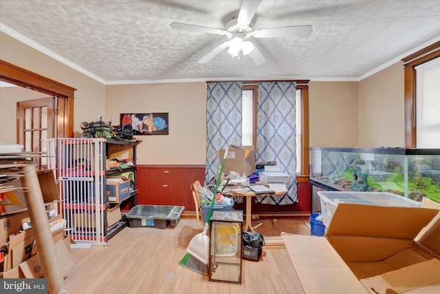 interior space with wood walls, ceiling fan, ornamental molding, and hardwood / wood-style floors