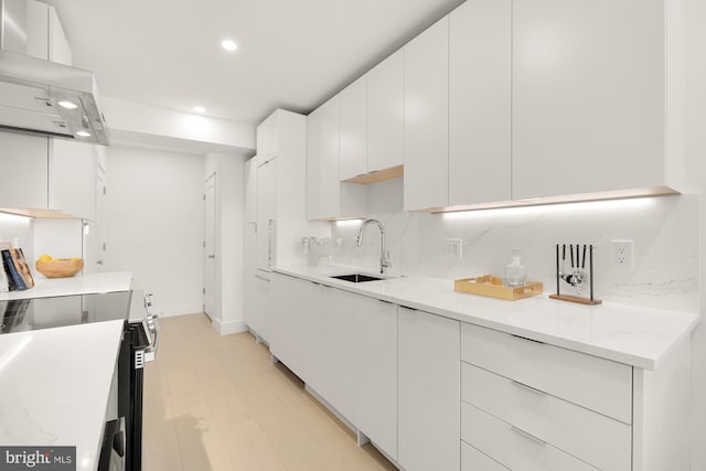 kitchen featuring decorative backsplash, electric range, wall chimney exhaust hood, white cabinets, and sink