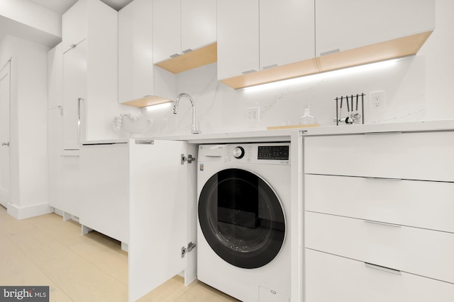 laundry room featuring sink, light hardwood / wood-style flooring, and washer / clothes dryer