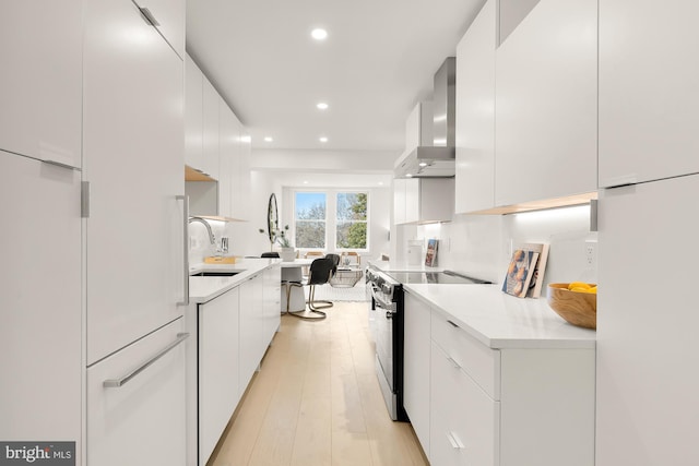 kitchen featuring wall chimney exhaust hood, white cabinets, and electric range