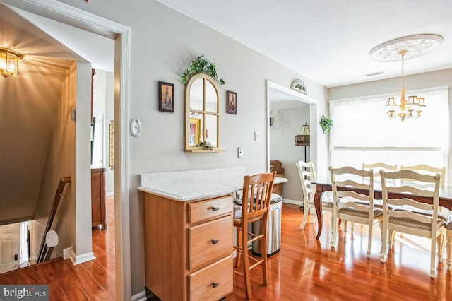 dining area with visible vents, baseboards, an inviting chandelier, and wood finished floors