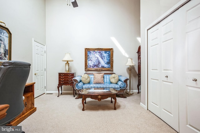 carpeted office space with baseboards, a high ceiling, and ceiling fan