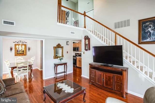 living room with visible vents, stairway, baseboards, and wood finished floors