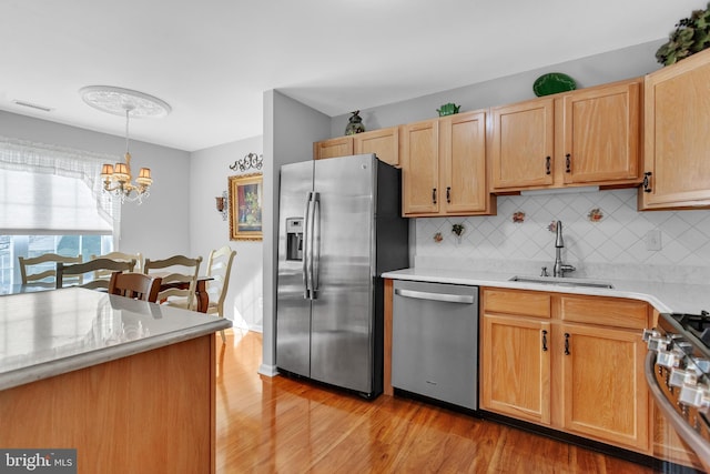 kitchen featuring visible vents, light countertops, light wood-style flooring, stainless steel appliances, and a sink