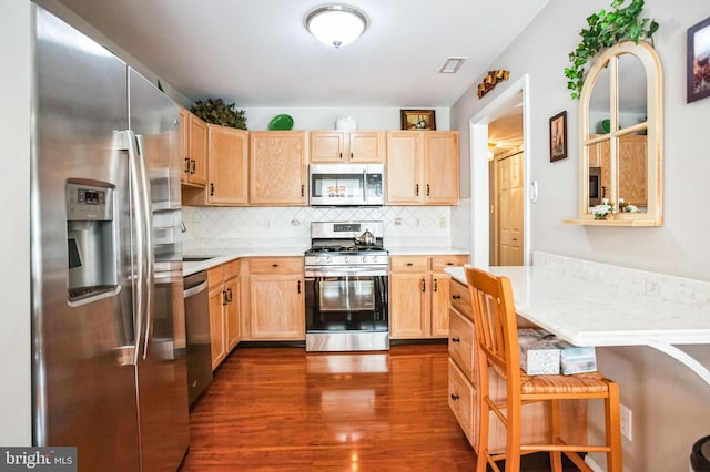 kitchen with light brown cabinets, dark wood finished floors, stainless steel appliances, light countertops, and tasteful backsplash