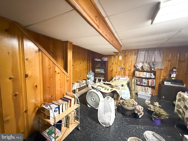 basement with a paneled ceiling and wood walls