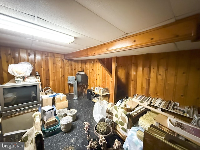 misc room featuring a paneled ceiling and wood walls