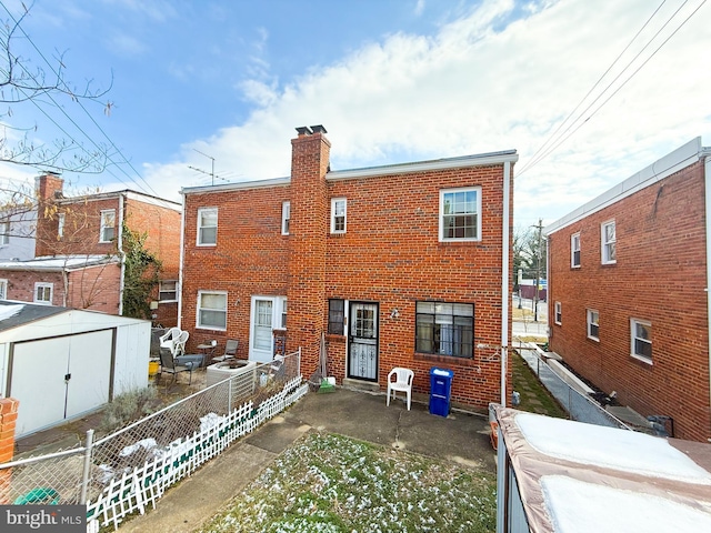 rear view of property with a storage shed and a patio