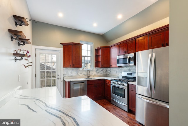 kitchen with lofted ceiling, sink, tasteful backsplash, appliances with stainless steel finishes, and dark hardwood / wood-style flooring