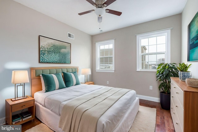 bedroom featuring multiple windows, dark wood-type flooring, and ceiling fan