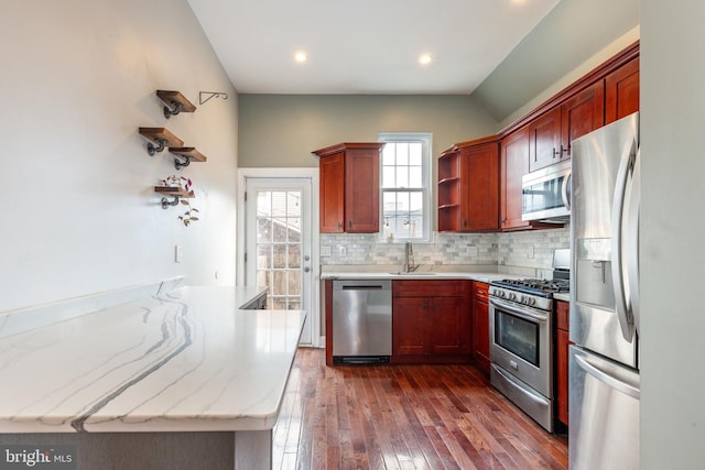 kitchen with sink, dark wood-type flooring, appliances with stainless steel finishes, backsplash, and light stone counters