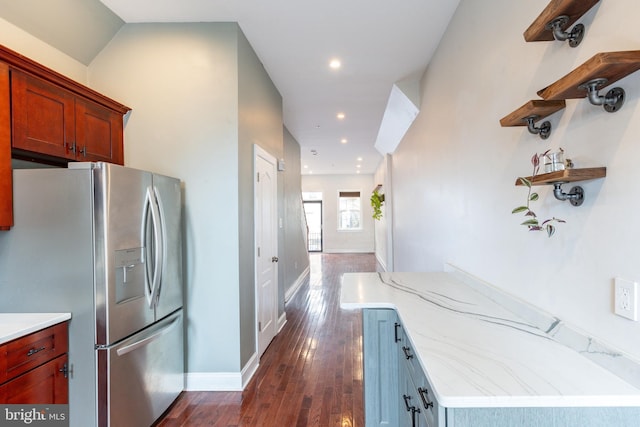 kitchen featuring dark hardwood / wood-style floors, stainless steel fridge, and light stone countertops