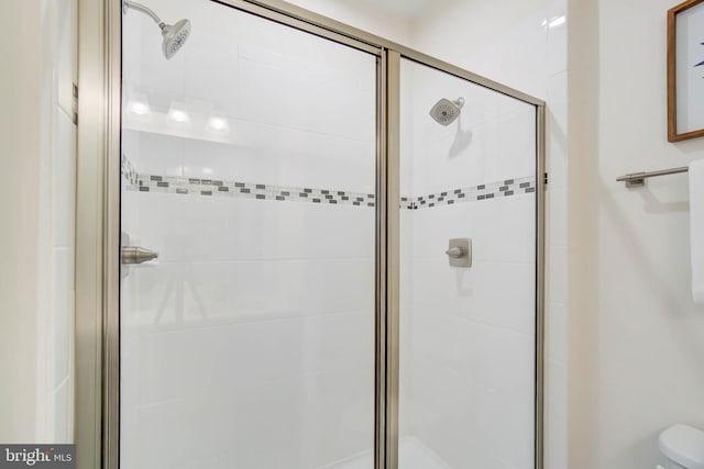 bathroom featuring toilet and a shower with shower door