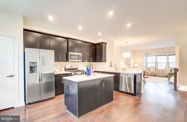 kitchen featuring pendant lighting, appliances with stainless steel finishes, light hardwood / wood-style flooring, and a kitchen island