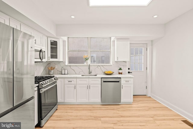 kitchen featuring light wood-type flooring, appliances with stainless steel finishes, sink, and white cabinetry