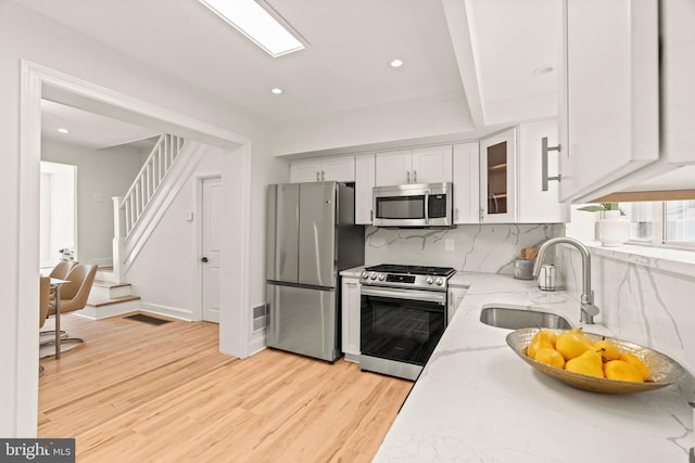 kitchen with light stone countertops, sink, white cabinetry, and stainless steel appliances