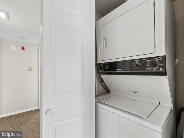 clothes washing area with stacked washer and clothes dryer and carpet flooring