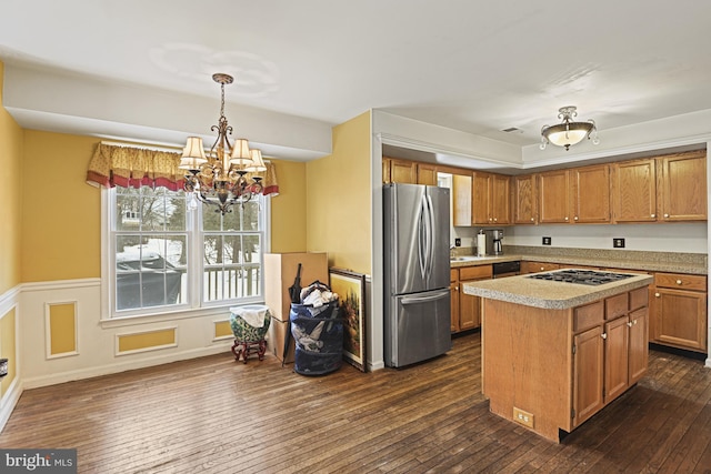 kitchen with a center island, gas cooktop, pendant lighting, dark hardwood / wood-style flooring, and stainless steel fridge