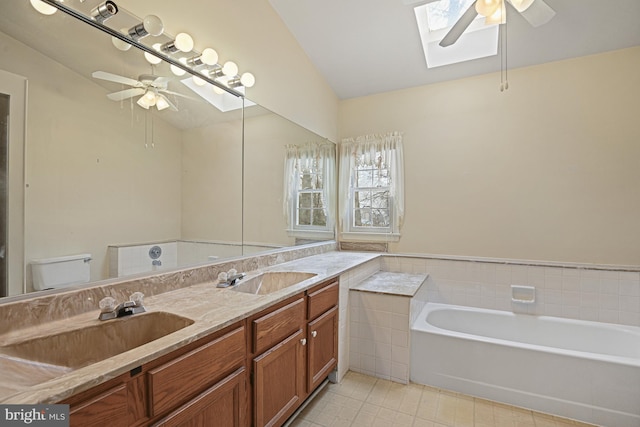 bathroom featuring a bathtub, toilet, lofted ceiling with skylight, vanity, and ceiling fan