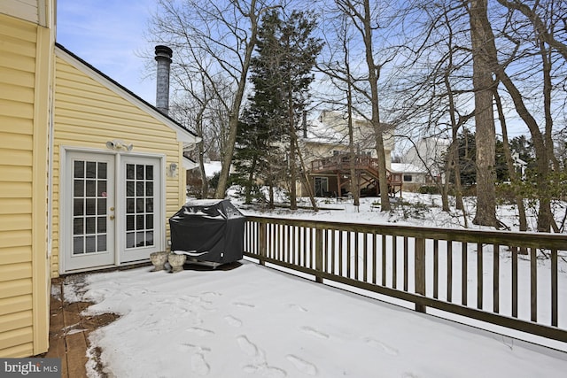 snow covered deck featuring french doors and a grill