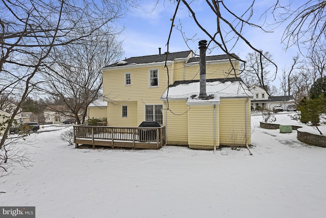 snow covered back of property featuring a deck