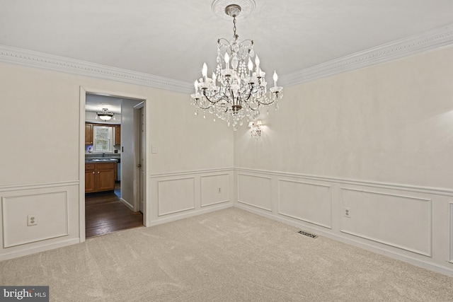 unfurnished dining area with carpet, ornamental molding, and an inviting chandelier