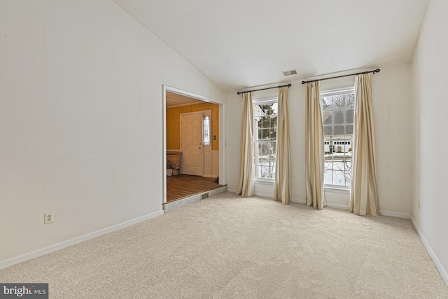 carpeted empty room with vaulted ceiling