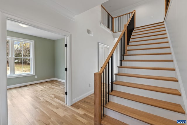 stairway with wood-type flooring and ornamental molding