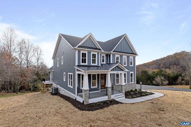 view of front of home with covered porch, a front lawn, and central AC