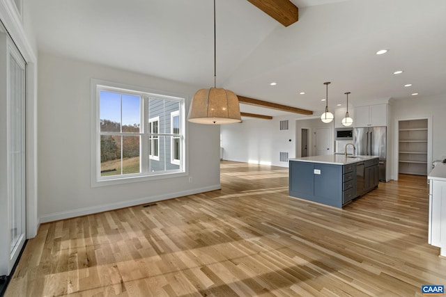 kitchen with hanging light fixtures, light hardwood / wood-style floors, white cabinetry, and a center island with sink