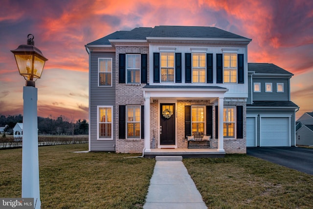 1335 Ashton Rd, Mechanicsburg, PA 17055 - view of front of house featuring aphalt driveway, covered porch, a front lawn, brick siding, and an attached garage