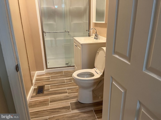 bathroom with a shower with shower door, toilet, and vanity