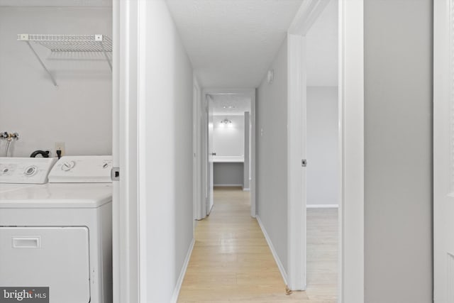 laundry room with a textured ceiling, washer and dryer, and light wood-type flooring