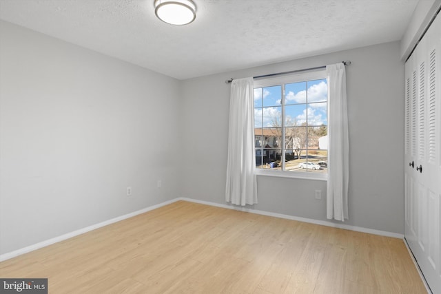 spare room with a textured ceiling and light hardwood / wood-style floors