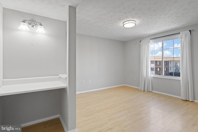 spare room with a textured ceiling and light hardwood / wood-style floors