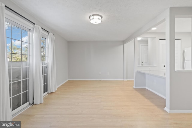 spare room with a textured ceiling and light wood-type flooring