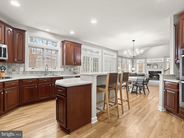 kitchen with open floor plan, light countertops, a sink, and pendant lighting