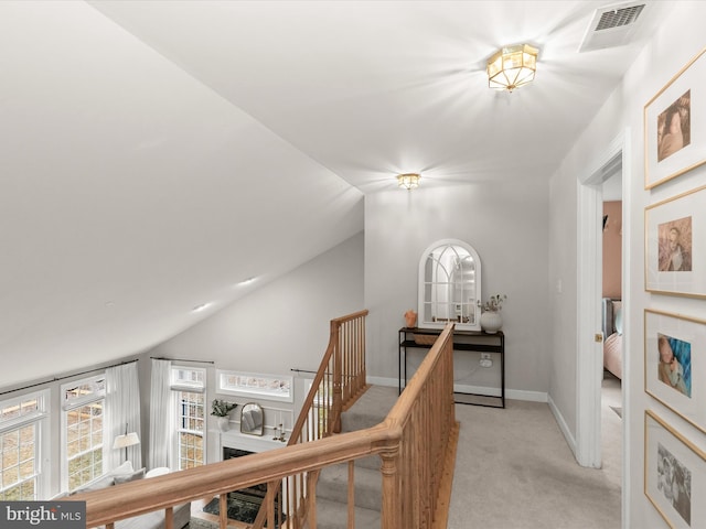 corridor with lofted ceiling, light carpet, an upstairs landing, visible vents, and baseboards