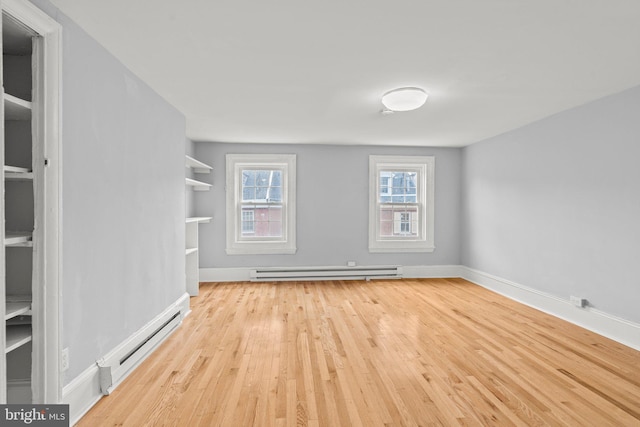 empty room featuring a baseboard heating unit and light hardwood / wood-style flooring