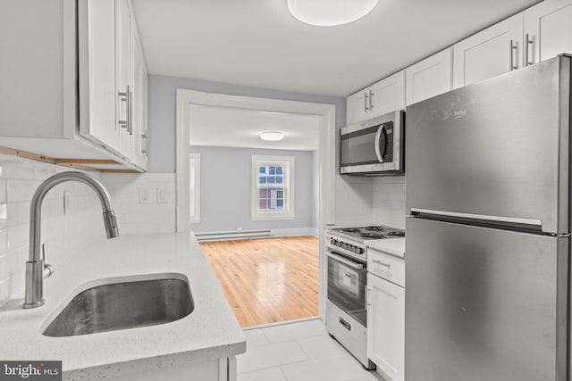 kitchen featuring backsplash, sink, white cabinetry, appliances with stainless steel finishes, and baseboard heating