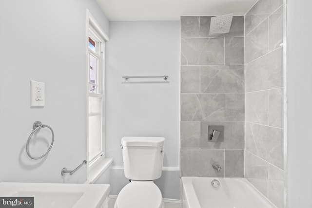 bathroom featuring toilet and tiled shower / bath